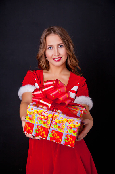 Beautiful girl wearing santa claus clothes with christmas gift - Фото, изображение