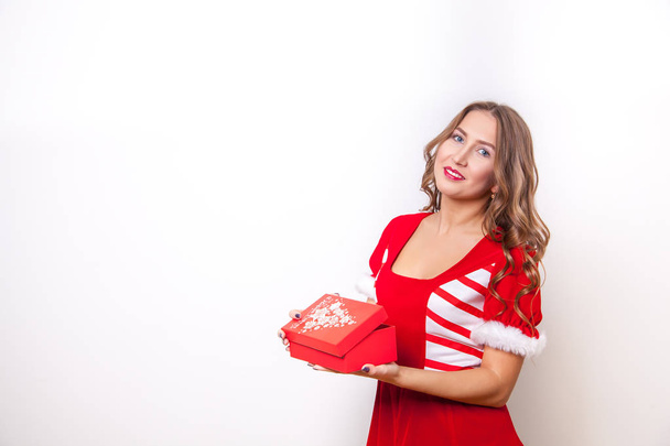 Beautiful girl dressed as Santa Claus opens a gift - 写真・画像