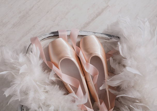 Chaussures pointes de ballet rose et plumes sur fond de bois blanc
 - Photo, image
