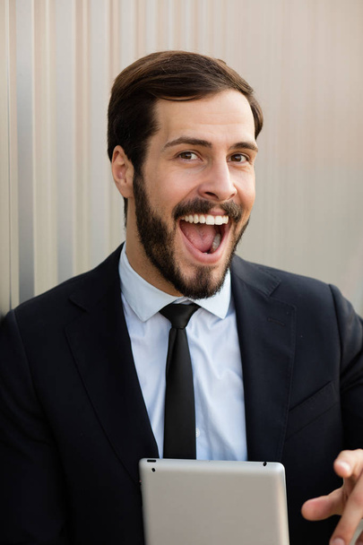 clouse up of a smiling business man with grey tablet - Fotó, kép