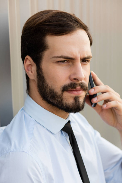 clouse up of a man in blue shirt and tie talking at cellphone - Foto, Bild