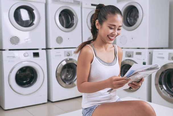 girl reading magazine when waiting for washing machine - Photo, Image