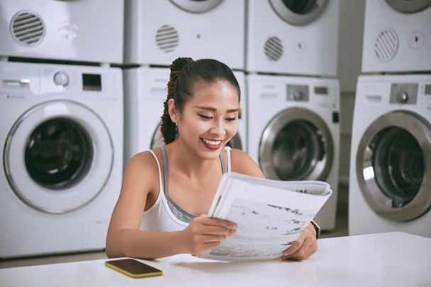 woman reading newspaper in laundromat - Foto, immagini
