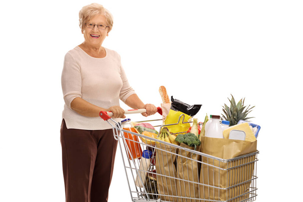 Cheerful mature lady with shopping cart - Фото, зображення