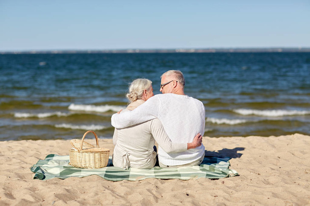 happy senior couple hugging on summer beach - Фото, изображение