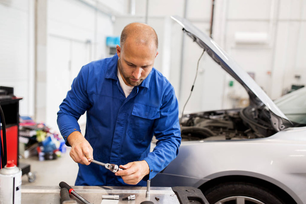 mechanic man with wrench repairing car at workshop - Photo, image