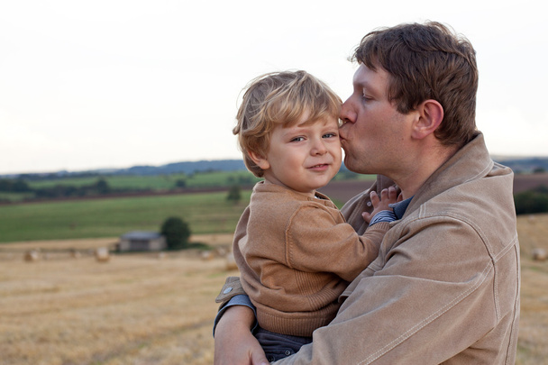 Young father giving son kiss on golden straw field - Foto, immagini