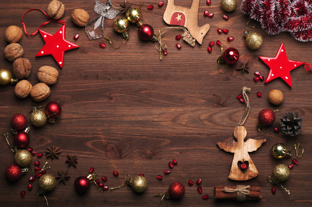 Año Nuevo o fondo de Navidad (fondo de pantalla). Decoraciones navideñas y oropel, nueces, anís estrellado, conos de pino, palitos de canela y otros atributos de la Navidad sobre fondo de madera marrón. Espacio para texto
 - Foto, imagen