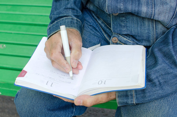Hombre de edad está tomando notas en el planificador diario
 - Foto, Imagen