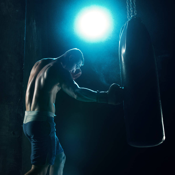 Male boxer boxing in punching bag - Foto, afbeelding