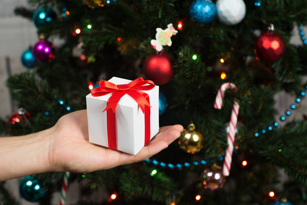 Man holding gift box near Christmas tree - Фото, изображение
