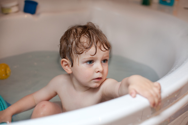 Adorable toddler boy with blond hairs taking bath - Fotó, kép