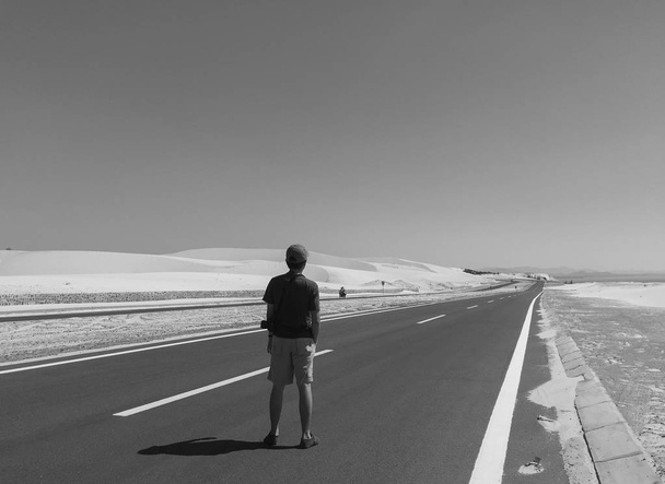 Ein Mann steht auf der neuen Autobahn zur kleinen Siedlung. - Foto, Bild