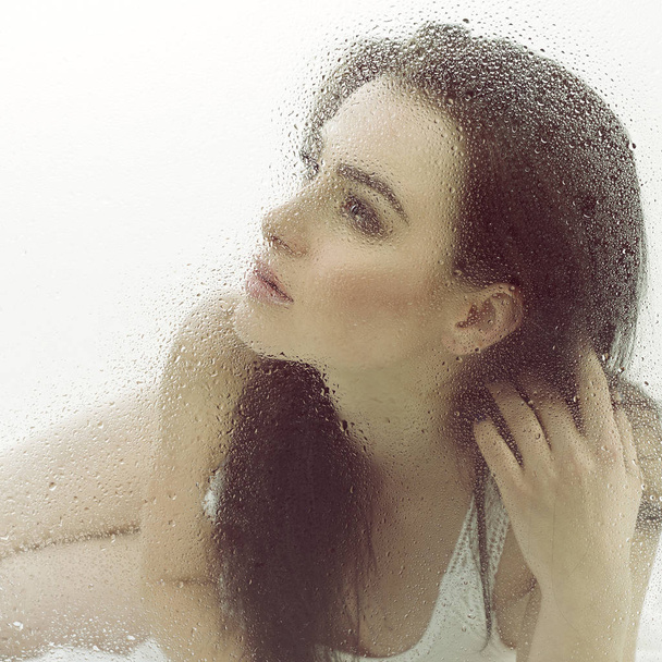 Beautiful woman in wet window - Photo, image