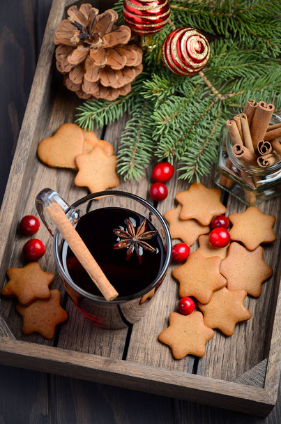 Χριστουγεννιάτικο ζεστό κρασί. Έννοιας διακοπές διακόσμηση με κλαδιά έλατου, μελόψωμο Cookies και Cranberries στο σκοτεινό ξύλινο δίσκο.   - Φωτογραφία, εικόνα