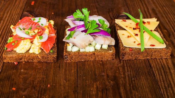 Smorrebrod - sándwich abierto danés con pescado, arenque, queso
 - Foto, imagen