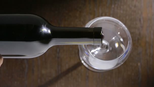 Pouring red wine into the glass against wooden background. top view - Video