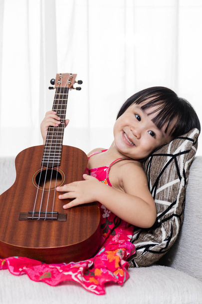 Happy Asian Chinese little girl playing ukele - Fotó, kép