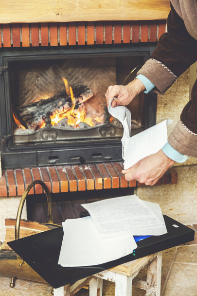 Hands tear sheets in bathrobe in front of burning fireplace - Foto, imagen
