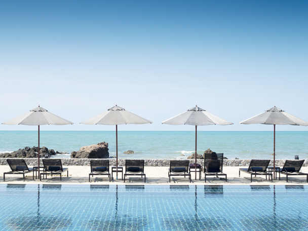 Sombrilla y piscina en complejo hotelero con playa de mar backgr
 - Foto, Imagen
