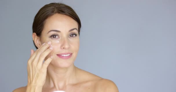 Hermosa mujer joven aplicando crema facial
 - Metraje, vídeo