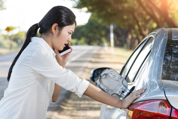 Autó olaj le, és a fiatal nő kipróbálás-hoz hív segítséget a telefon - Fotó, kép