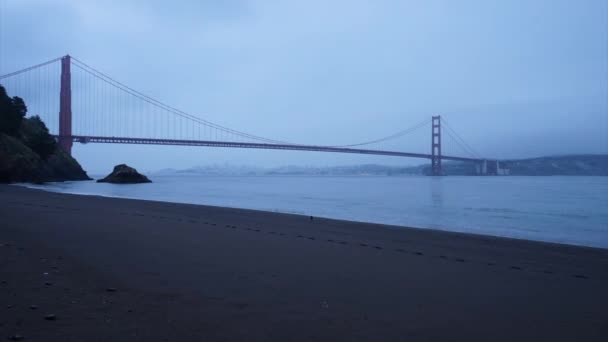 Zeitraffer-Ansicht des finsteren Strandes durch goldene Torbrücke - Filmmaterial, Video