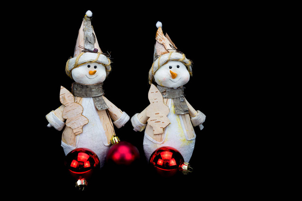 Two snowmen figurines with red baubles on black - Photo, Image