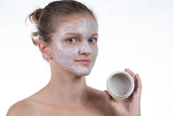 Two cosmetic mask of gray clay with scrub and cream on the face  - Photo, Image