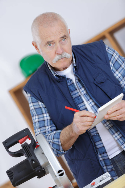 senior carpenter holding clipboard and making notes - Zdjęcie, obraz