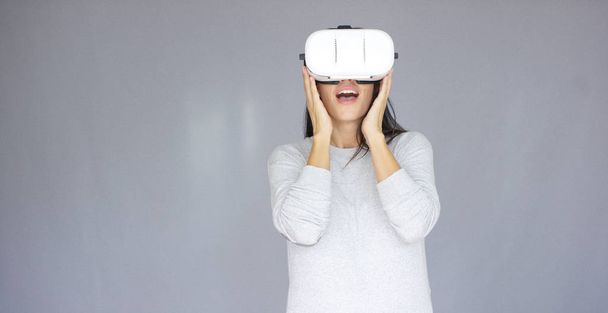 aufgeregte Frau beobachtet etwas auf ihrem Virtual-Reality-Helm - Foto, Bild