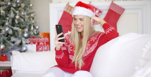 Cep telefonu kullaranarak Noel kıyafeti genç mutlu sarışın kız - Fotoğraf, Görsel