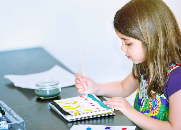 Portret van schattig meisje geconcentreerd tijdens het schilderen - Foto, afbeelding