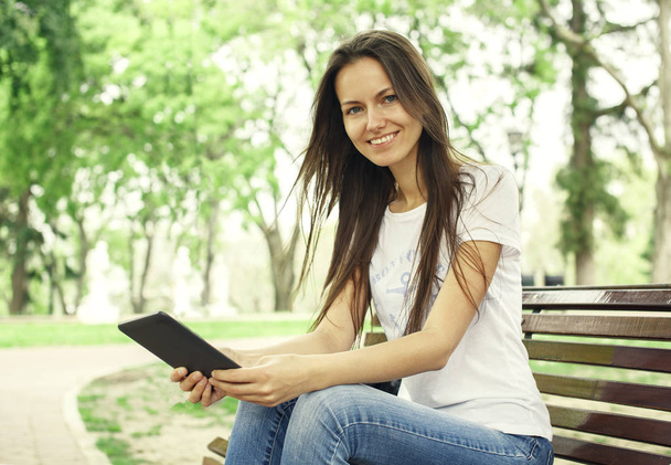 Beautiful girl with e-book in the park - 写真・画像