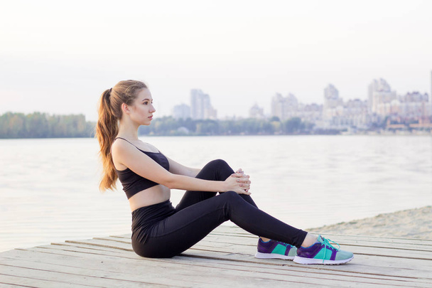 Молодая женщина отдыхает во время тренировки упражнения на открытом воздухе в м
 - Фото, изображение