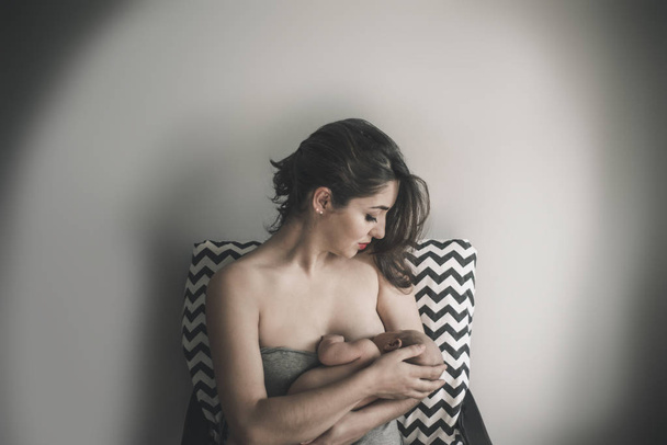 Молодая мать держит своего новорожденного ребенка. Мама кормит ребенка. - Фото, изображение
