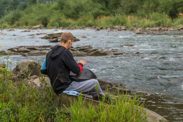 Adam asmak davulunun nehir kenarında oynuyor. Karpatlar. Ukrayna. - Fotoğraf, Görsel