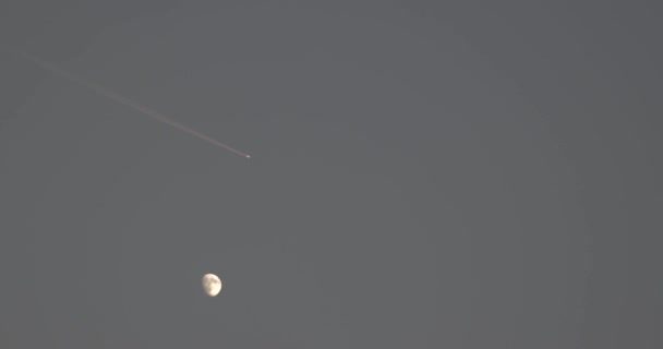 Mond trifft Düsenflugzeug, das Treibstoffspur bei Sonnenuntergang passiert - Filmmaterial, Video