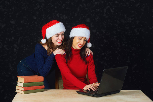 Two young girls in red Christmas hats Santa write letter to Santa - Photo, image