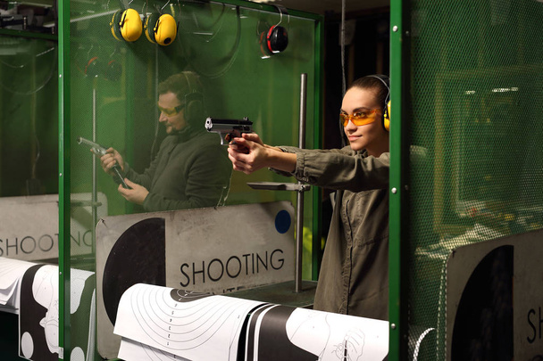Woman shoots a gun at a shooting range. - Photo, image