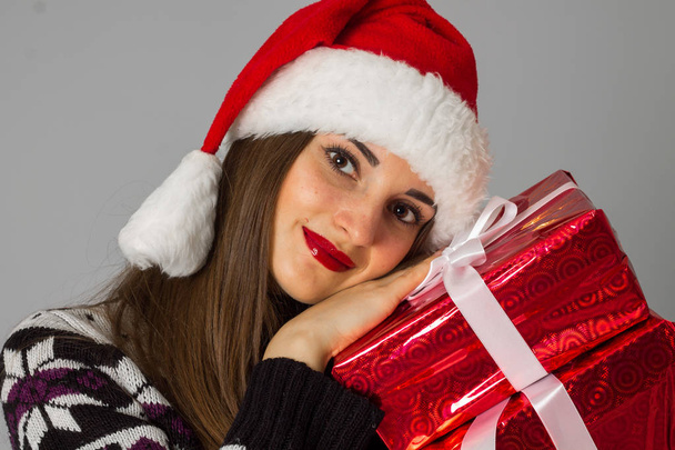 woman in warm sweater and santa hat with red gift - Fotó, kép