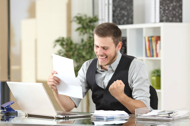 Excited businessman reading a letter at office - Foto, immagini