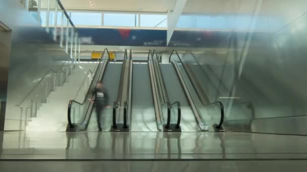 As pessoas usam uma escada rolante no terminal do aeroporto ou no shopping. Os rostos dos povos são indistinguíveis
 - Filmagem, Vídeo