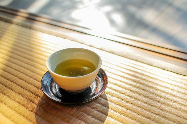 Giornata termale del tè pomeridiano. Una tazza di tè verde su un tappeto tradizionale giapponese, tatami
 - Foto, immagini