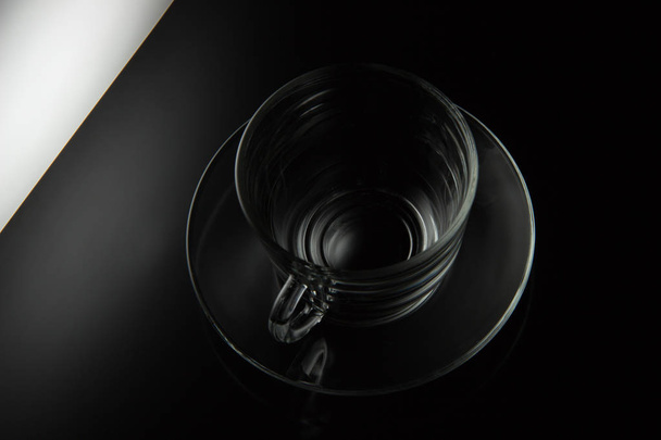 Taza vacía transparente de vidrio de té y platillo en un backgro negro
 - Foto, imagen