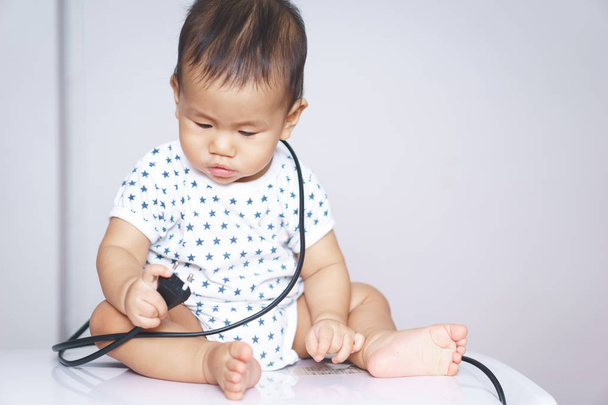Asiatisches Baby neugierig auf elektronische Stecker - Foto, Bild