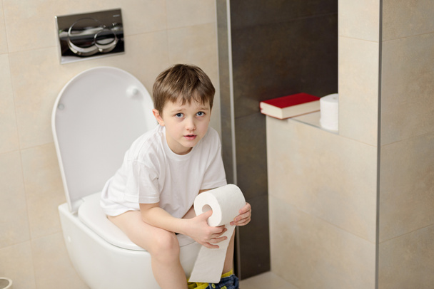 Pequeno menino de 7 anos sentado no banheiro
. - Foto, Imagem