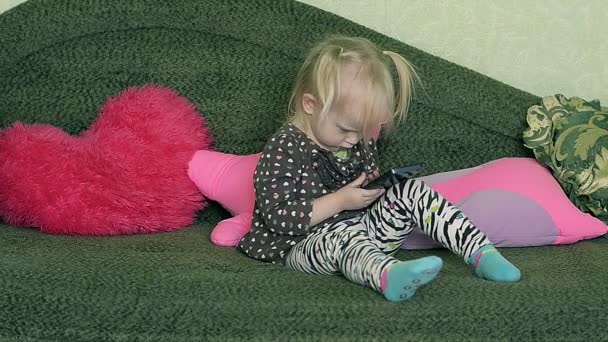 Küçük kız evde Smartphone ile kanepede otururken - Video, Çekim