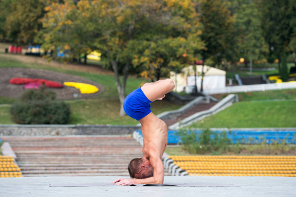 Athletic man doing yoga asanas in the park - Foto, imagen