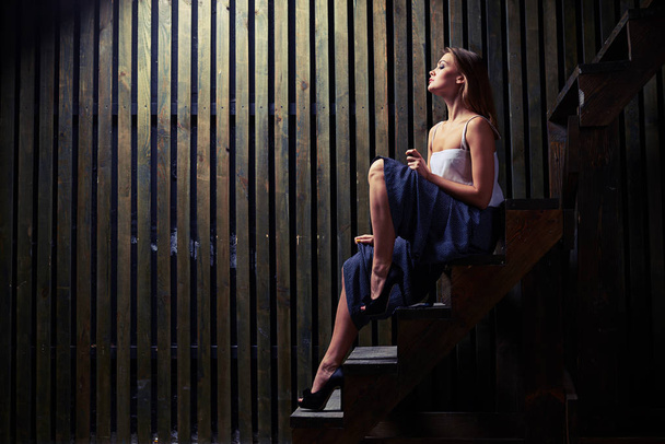Εμπνευσμένη γυναίκα με γυμνή άπαχο πόδια που θέτουν στην ξύλινη σκάλα στο δ - Φωτογραφία, εικόνα